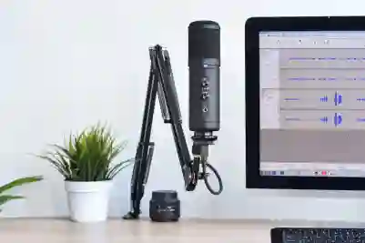 Mikrofoni ja tietokone työpöydällä, jossa on musiikki sovellus avoinna.