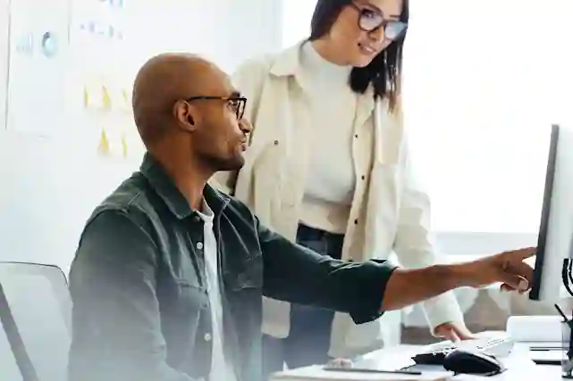 Henkilö osoittaa toiselle henkilölle tietokoneen ruutua