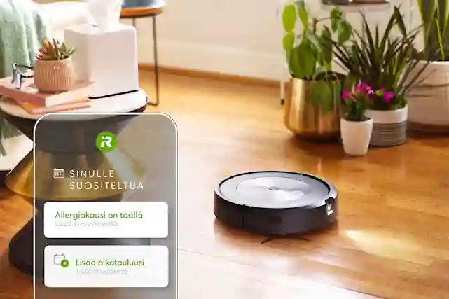 Robotdammsugare på golvet och en mobilapp på en telefonskärm i förgrunden.