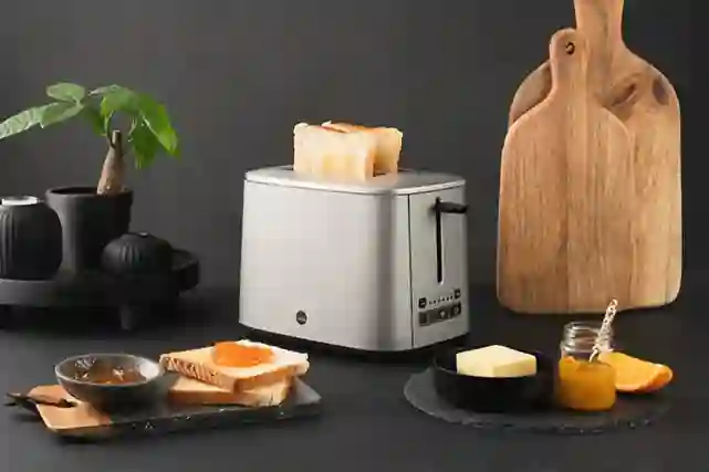 Wilfa Titanium CT-1000T -leivänpaahdin pöydällä. Vieressä paahdettua leipää juustoa ja hilloja