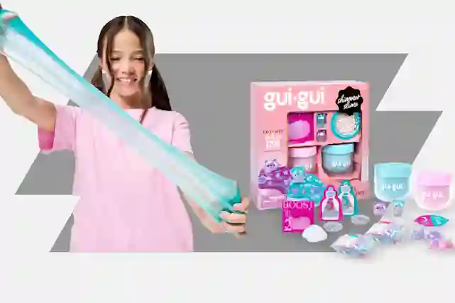 Tyttö venyttää turkoosivihreää Gui-Gui Shimmer slimea, vieressä gui-gui shimmer slime -lelusetti vaaleanpunaisessa pakkauksessa.