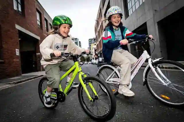 Kaksi lasta ajaa urbaanissa maisemassa Beanyn ja Inseran polkupyörillä ilosta kiljuen. Tutustu! (Ai-työkalulla tehty kuva).