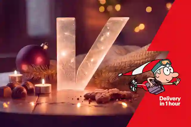 A Verkkokauppa.com V-logo Christmas decoration on a wooden table in a festive room. Delivered in under an hour!