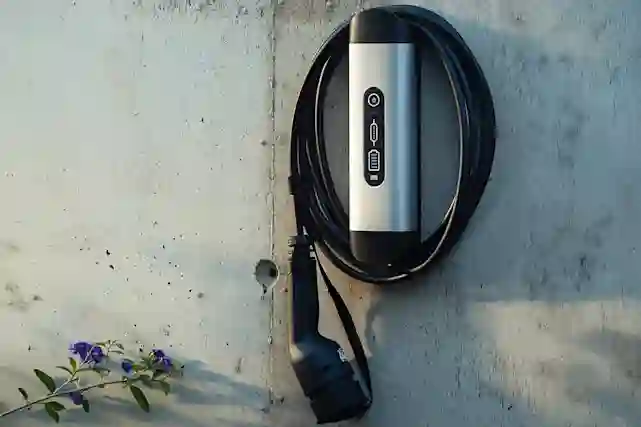 An electric car charging station mounted on a concrete wall with the cable wrapped around the unit.