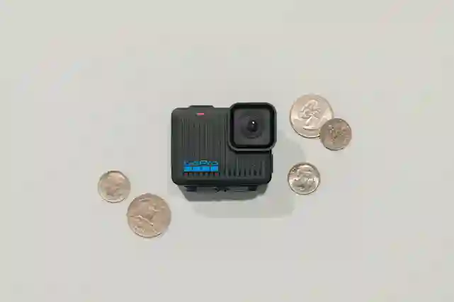 Pieni GoPro HERO-kamera, ympärillä kolikoita.