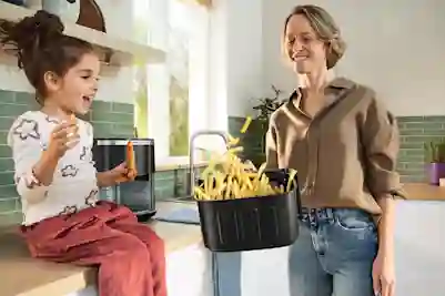 Henkilö ravistaa airfryerin astiassa olevia ranskalaisia.