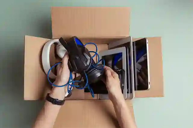 Henkilö pakkaa pahvilaatikkoon käytettyjä laitteita