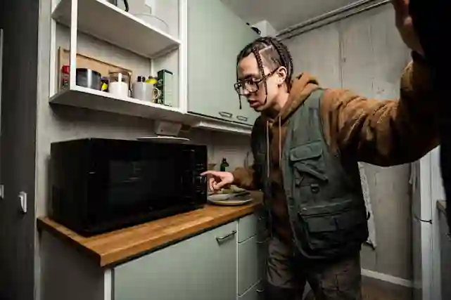 Henkilö käyttää mikroaatouunia pienessä urbaanissa keittiössä. 