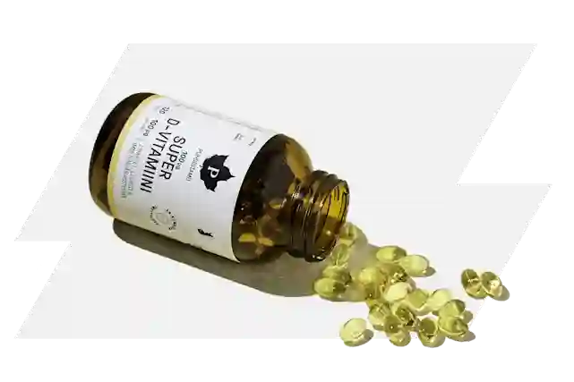 Brown glass bottle with yellow vitamin D capsules spilling onto a white surface.