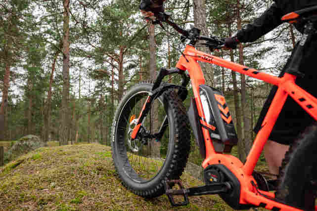 Pyöräilijä metsässä GZR-sähköpyörällä. Lähikuva pyörän akusta.