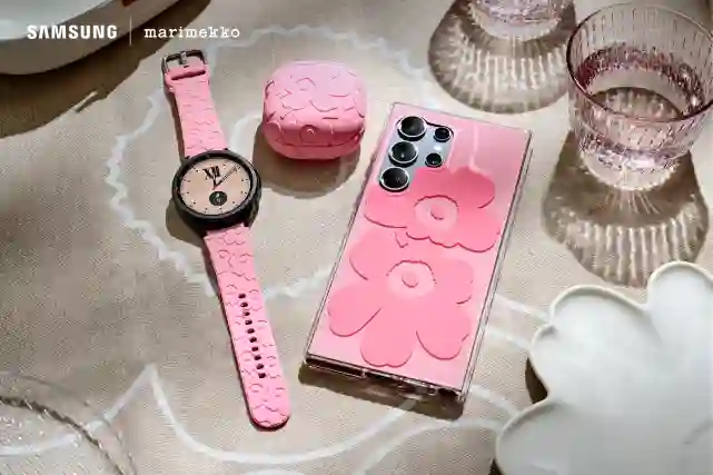 Kuva Samsung x Marimekko yhteistyössä tehdyistä kuorista puhelimessa ja lisätarvikkeista Galaxy Watchissa ja Galaxy Buds -kotelon ympärillä. Niissäon pinkkiä Unikko-kuosia. Taustalla Marimekon pöytäliina.