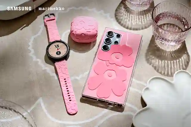 Kuva Samsung x Marimekko yhteistyössä tehdyistä kuorista puhelimessa ja lisätarvikkeista Galaxy Watchissa ja Galaxy Buds -kotelon ympärillä. Niissäon pinkkiä Unikko-kuosia. Taustalla Marimekon pöytäliina.