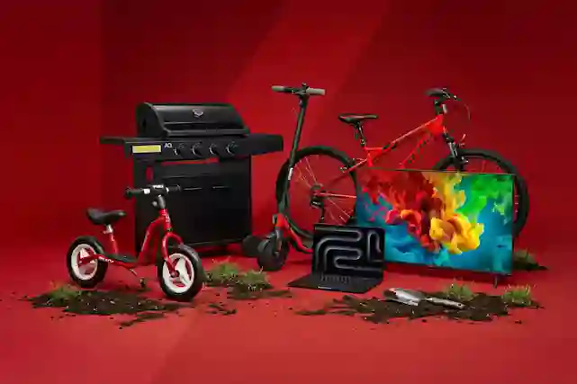 Punaisella taustalla valikoima ajankohtaisia tuotteita: sähköpotkulauta, polkupyöriä, kaasugrilli, televisio ja kannettava tietokone.