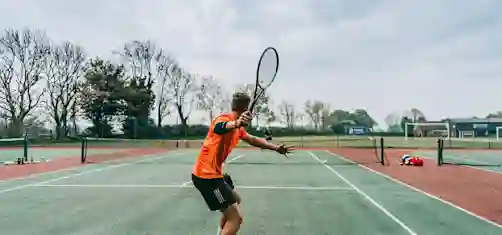 Mies pelaa tennistä kentällä.