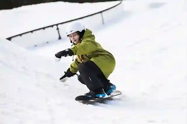 Lapsi laskee lumilaudalla rinnettä pitkin alas