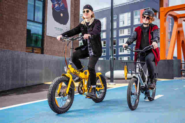 Kaupunkipyöräilijät ajavat GZR-sähköpyörällä. Toisella keltainen pyörä ja toisella hopea.