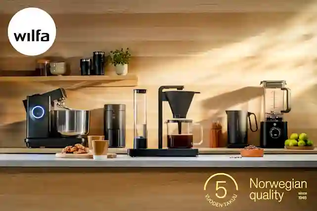 Wilfa-logo ja taustalla puinen keittiö, jossa Wilfan kahvikeitin keskiössä.