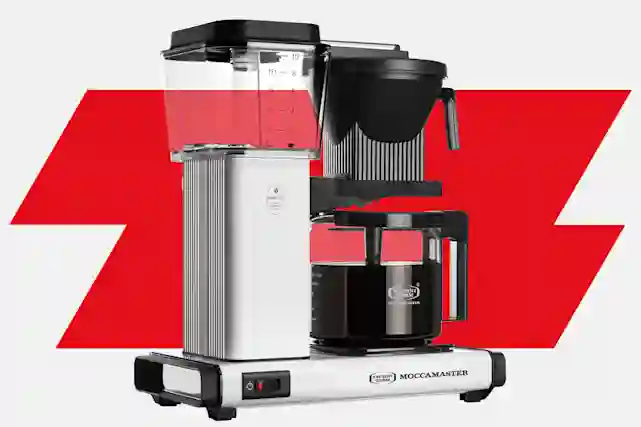 Moccamaster One Switch kahvinkeitin harmaapunaisella taustalla.