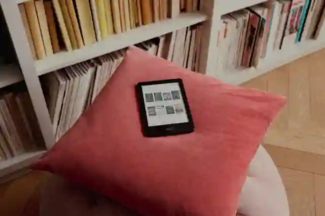 Kobo e-kirjan lukulaite tyynyn päällä kirjahyllyn vieressä.