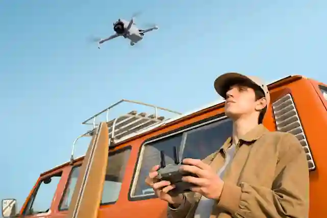 Henkilö ohjaa dronea kaukosäätimellä oranssin auton vieressä kirkkaalla taivaalla.