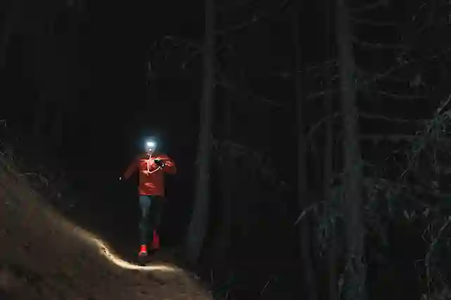 Ulkoilija juoksulenkillä pimeässä metsässä otsalamppu päällä