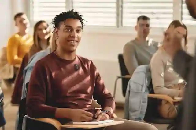 A smiling student in a classroom with other students.
