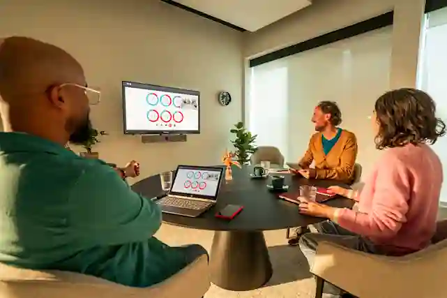 Barco ClickShare Bar Pro -videoneuvottelulaite kokoushuoneessa, jossa kolme henkilöä pitää palaveria