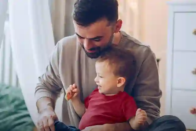 Henkilön sylissä taapero. Taaperilla Hooverin punainen paita.