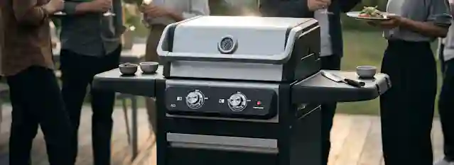 Anton Oliverin sähkögrilli ulkotilassa etualalla. Grillissä on suljettu kansi, lämpömittari ja säätönupit. Taustalla ihmiset seisovat ja nauttivat ruoasta ja juomasta.