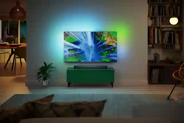 Olohuone, jonka seinällä TV, joka loistaa valoa taakseen seinälle.