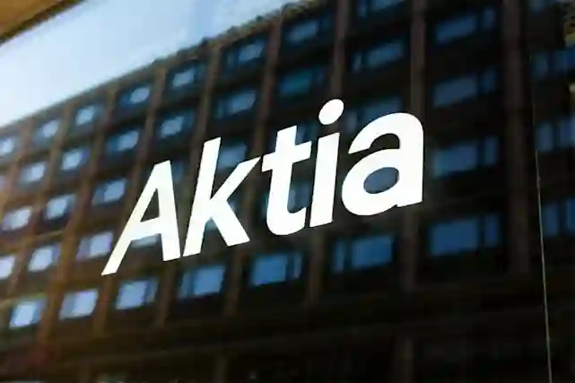 Tummassa ikkunan lasissa Aktian valkoinen logo