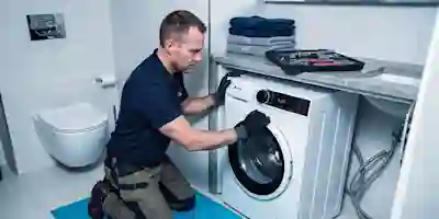 An installer is installing a white Ströme washing machine in the bathroom