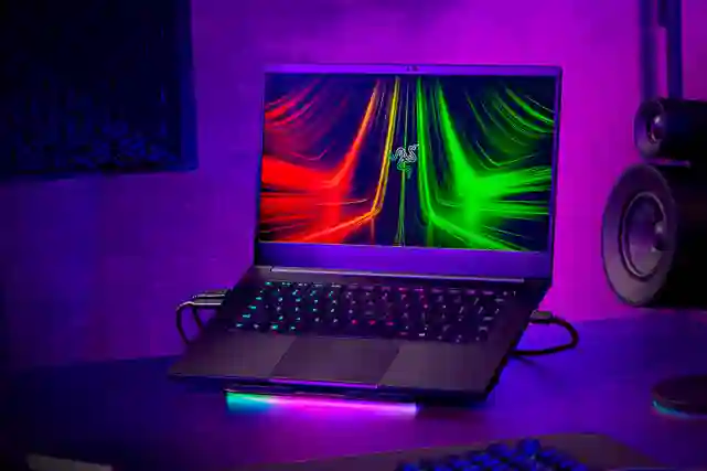 Razer Blade -pelikannettava pöydällä kaiuttimen ja näytön vieressä.