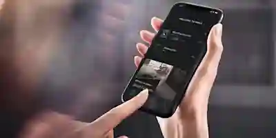 Händer håller en smartphone som visar Mieles smarta hem-app för styrning av hushållsapparater.