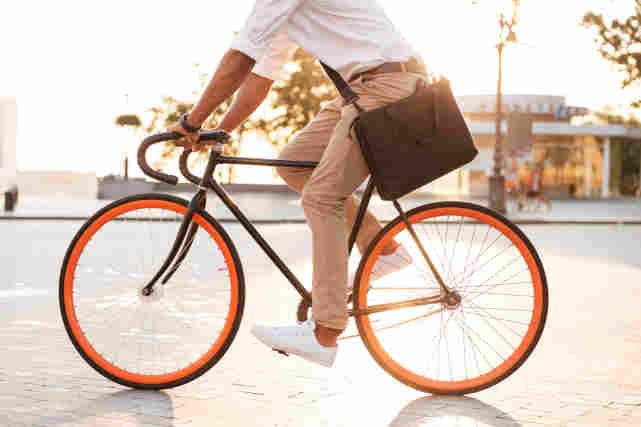 Pyoräilijä pyöräilee aurinkoisella säällä kaupungilla.
