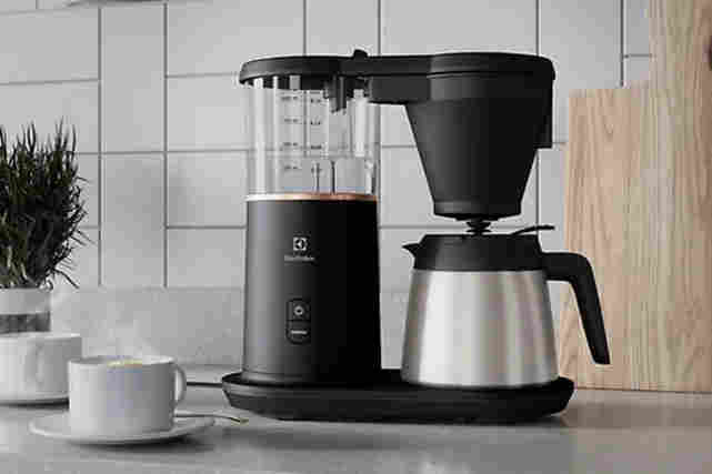 Keittiön pöydällä Electrolux E7CM1-6GB Explore 7-kahvinkeitin ja sen vieressä kahvikuppi.