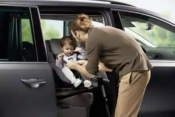 Mies kiinnittää lasta auton turvaistuimeen