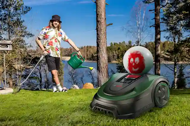 Kesähessu kastelee mökillä nurmikkoa kastelukannulla ja Wilson lentopallo ajelee robottiruohonleikkurilla.