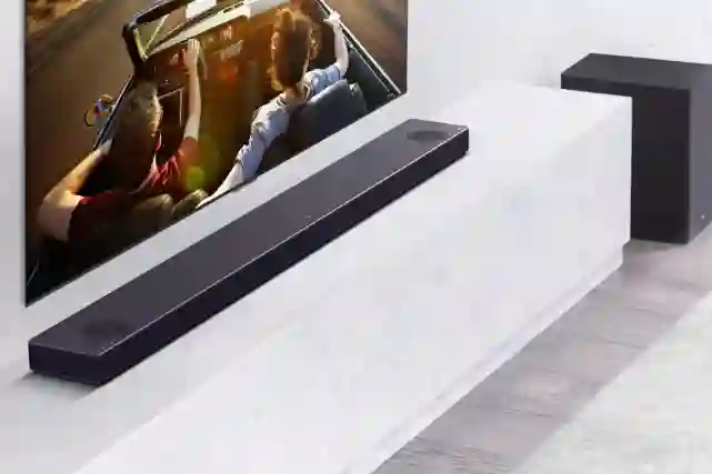LG:n soundbar television alapuolella. Lattialla tv-tason vieressä subwoofer.