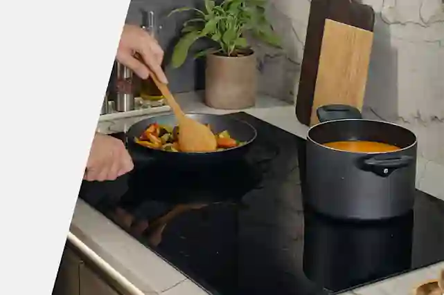 Ruoanvalmistusta Hooverin induktiotasolla. Pannulla paistossa vihanneksia ja kattilassa valmistuu kastike.