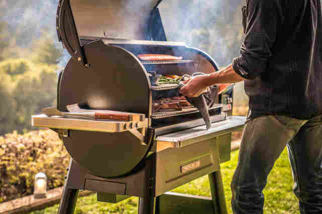 Henkilö grillaa Traeger Timberline -puupellettigrillillä ulkona