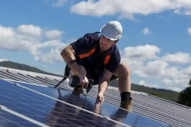 Mies asentaa katolle aurinkopaneeleja. Hän on ruuvivääntimellä laittamassa aurinkopaneelia kiinni peltikattoon. Tutustu aurinkopaneeleihin!