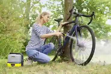 Nainen pesee pyörää akkupainepesurilla
