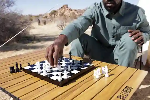 Mies pelaamassa Shakkia billebeinon taitettavalla shakkipöydällä. Shakkilauta asetettu Billebeinon puunväriselle retkipöydälle.