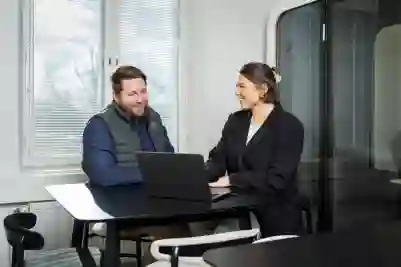 Mies ja nainen keskustelemassa tietokoneen äärellä toimistohuoneessa.