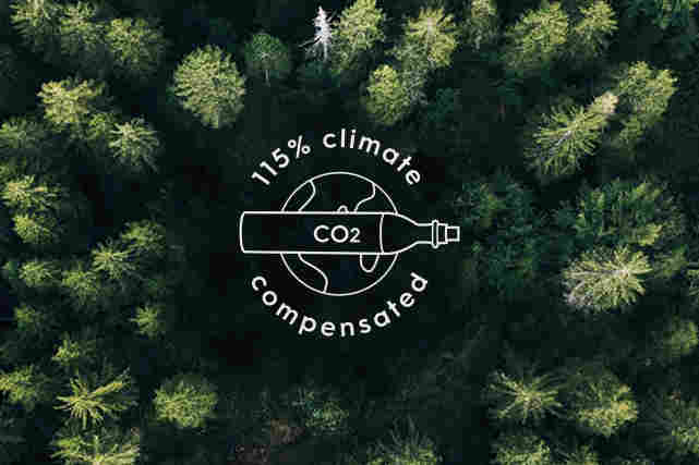Metsä kuvattu ylhäältä. Logo keskellä metsää jossa lukee:"115 % climate compensated CO2".