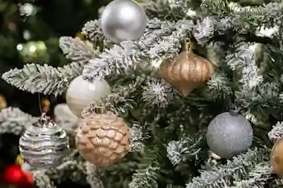 Snow-frosted Christmas tree decorated with silver and gold baubles.