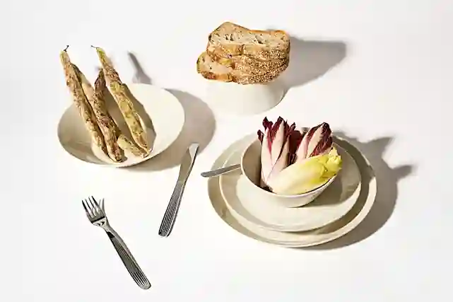 Iittalan Teema -sarjan tuotteita ruokapöydällä. Kulho, lautasia ja aterimia.