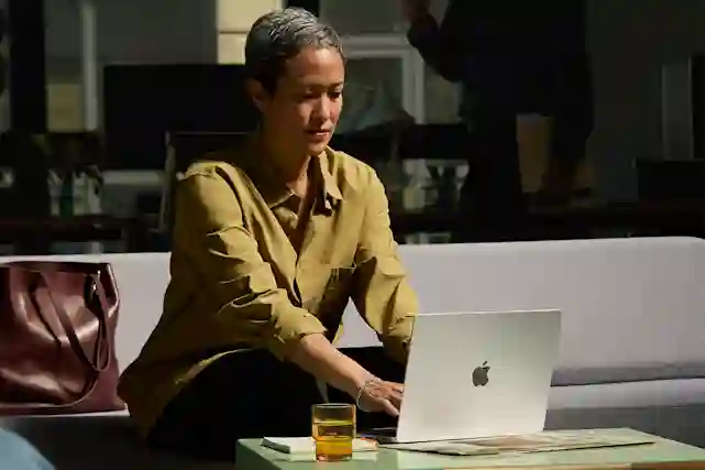 Naishenkilö istuu toimistolla edessään hopea MacBook Pro 14" M4 -kannettava
