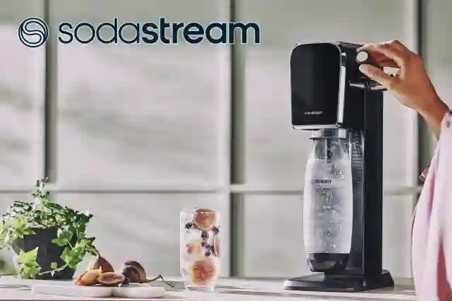 Sodastream-logo. Taustalla keittiönpöytä jossa on Sodastreamillä tehdään juotavaa.